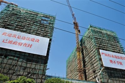 7月16日，北京宋庄徐宋路西侧几栋建筑上悬挂着巨幅标语，标明该建筑为小产权房，属于违法建筑。