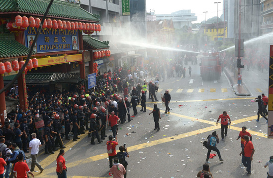 图为镇暴警察在吉隆坡的华人聚居地茨厂街向红衣人喷射水柱