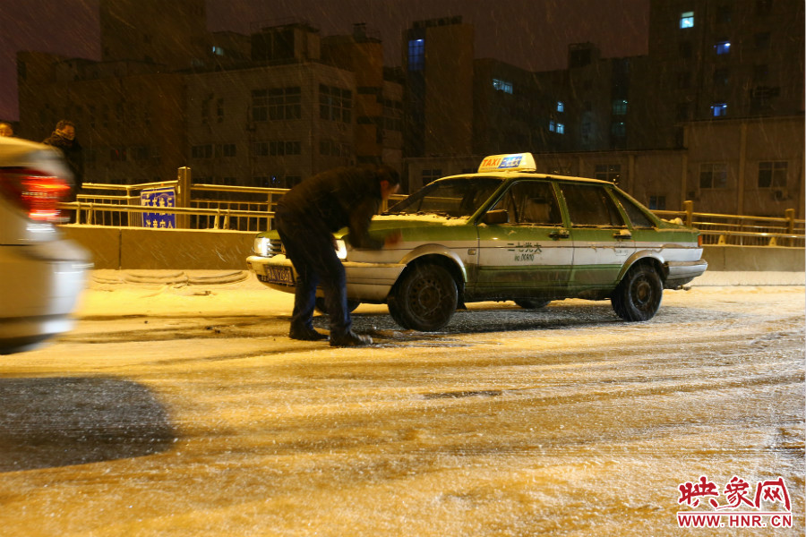 一位出租车司机在车轮前洒上雪，希望能增加轮胎的摩擦力。