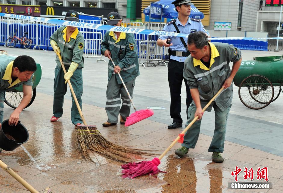 图为环卫工人在清理案发地点的血迹。