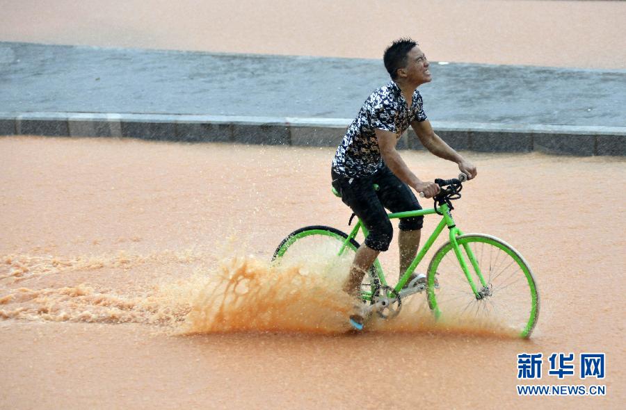 5月11日，一名行人在深圳街头冒雨骑行。