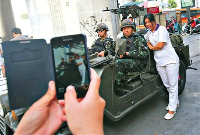 20日，泰国首都曼谷，一名妇女与执行军管任务的士兵合影。