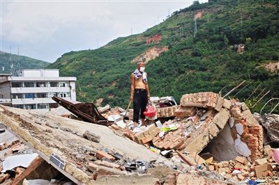 8月9日,龙头山镇,一位老者在自家房屋废墟上寻找家当。