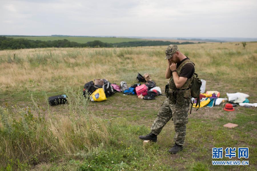 7月19日,在乌克兰顿涅茨克州马航MH17航班坠毁现场,一名武装人员在搜寻到的旅客行李旁打电话。