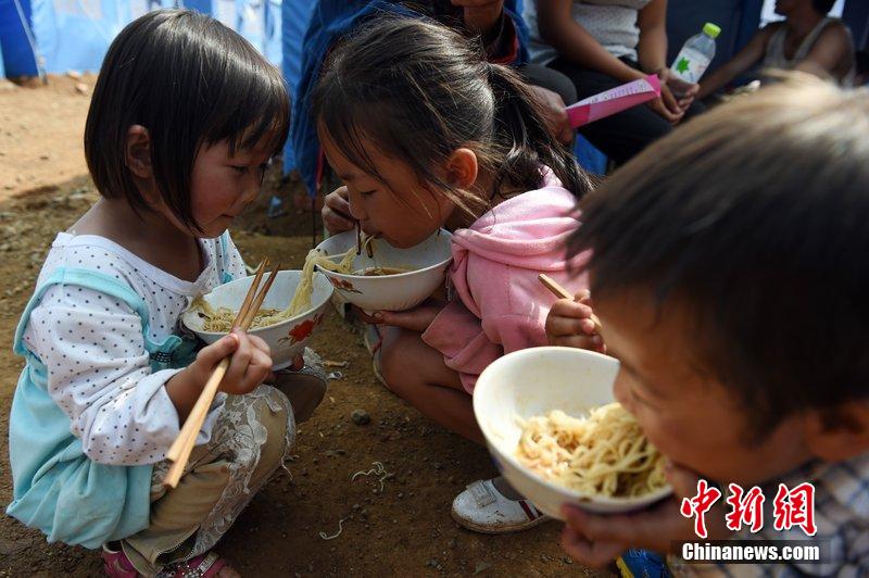 2014年8月6日，云南鲁甸龙头山灾区，儿童在帐篷外吃饭。