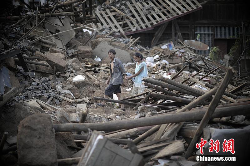 2014年8月5日，云南昭通龙头山镇老街，一对夫妻从居住房屋的废墟中走过。